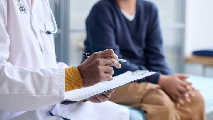 Metge prenent nota en una consulta