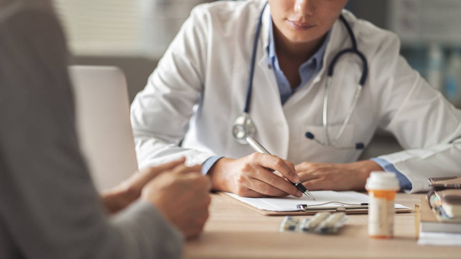 Doctor escrivint a la consulta mèdica amb un pacient