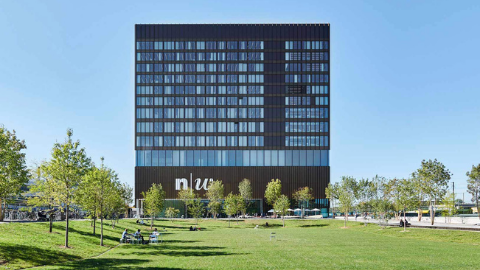 Fachada de un edificio de la FHNW con un descampado de césped delante. 