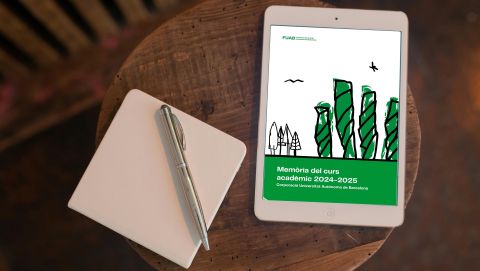 Una tablet mostra la portada de la Memòria de la Corporació UAB damunt d'una taula rodona