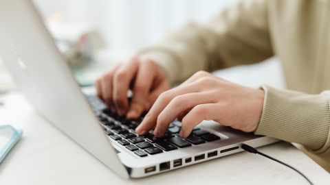 Mans escrivint a un portàtil