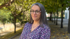 Anahí Casadesús, dona amb cabell llarg llis, ulleres i vestit morat estampat
