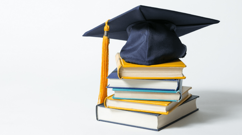 Barret de graduació a sobre d'una pila de llibres i el fons blanc
