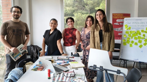 Un grup d'estudiants posa darrere una taula plena de material d'escriptori i una pissarra blanca
