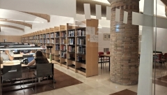 Perspectiva de la biblioteca amb estanteries amb llibres i estudiants asseguts a les taules