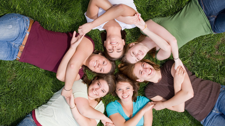 Noies contentes agafades de la mà mirant a dalt.